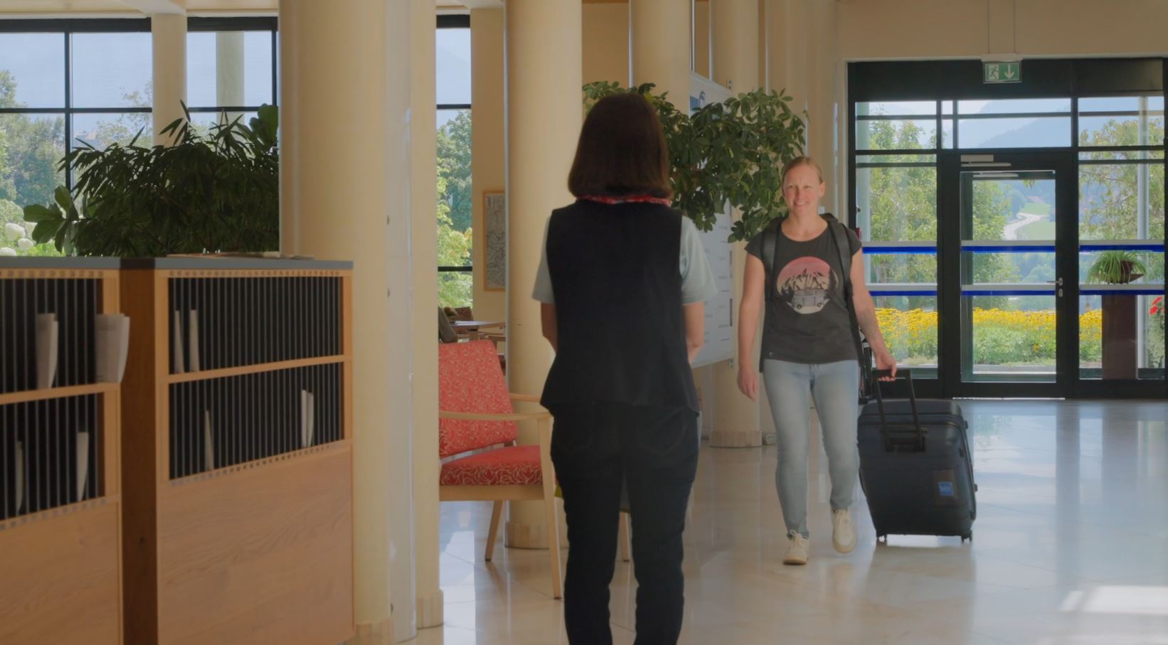 Junge Patientin mit Koffer wird an der Rezeption empfangen